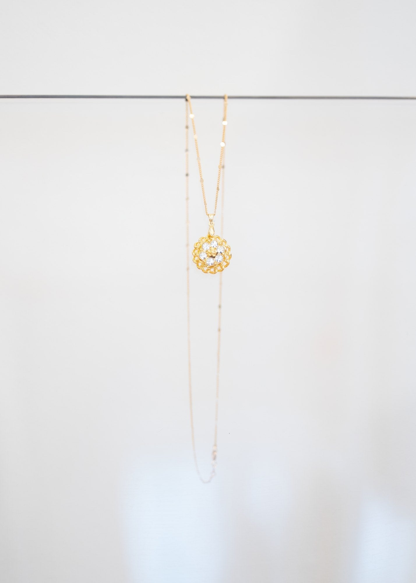 Collier « Rosace » — pendentif fleur dorée ajourée sertie de cristaux incolores, sur fine chaîne plaquée or à pastilles. Joyeux Joyaux par Alexandra Lambert.