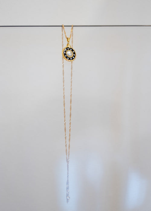 Collier « Perle Noire » — pendentif rond à perle blanche centrale entourée de cristaux sur émail noir et cerclage doré torsadé. Joyeux Joyaux par Alexandra Lambert.