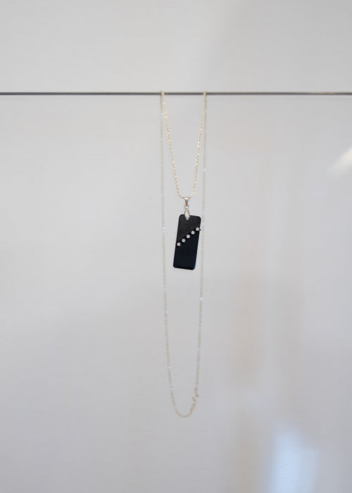 Collier « Obsidienne » — pendentif rectangulaire noir barré d'une diagonale de cinq cristaux, sur fine chaîne en argent. Joyeux Joyaux par Alexandra Lambert.