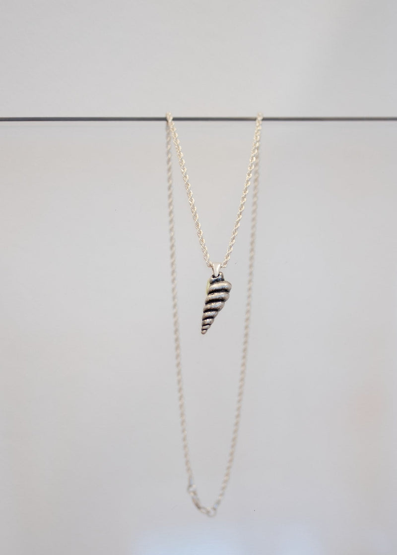 Collier « Conque » — pendentif coquillage en spirale, métal argenté patiné à cannelures, sur chaîne corde en argent. Joyeux Joyaux par Alexandra Lambert.